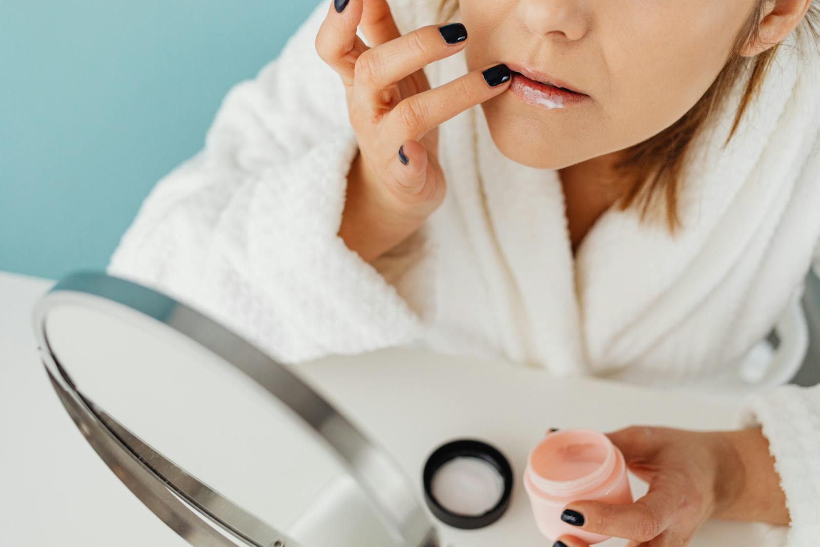 Woman applying niacinamide skincare in front of a mirror as part of her evening routine