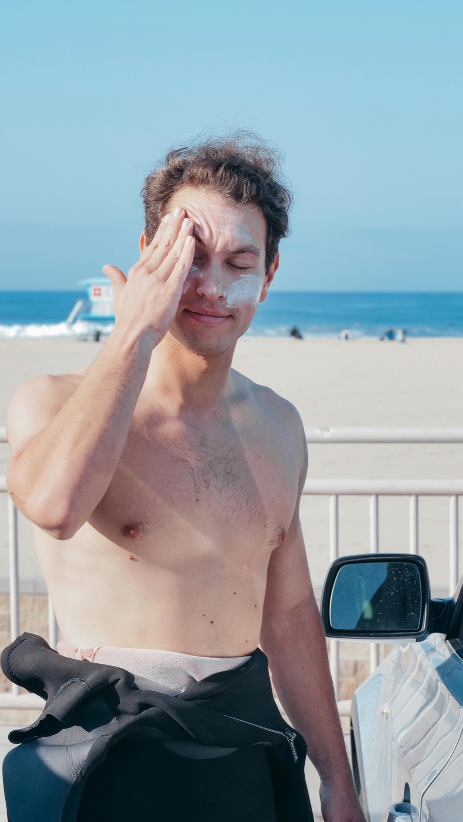 Hand applying broad-spectrum sunscreen with modern EU-approved UV filters on a sunny beach