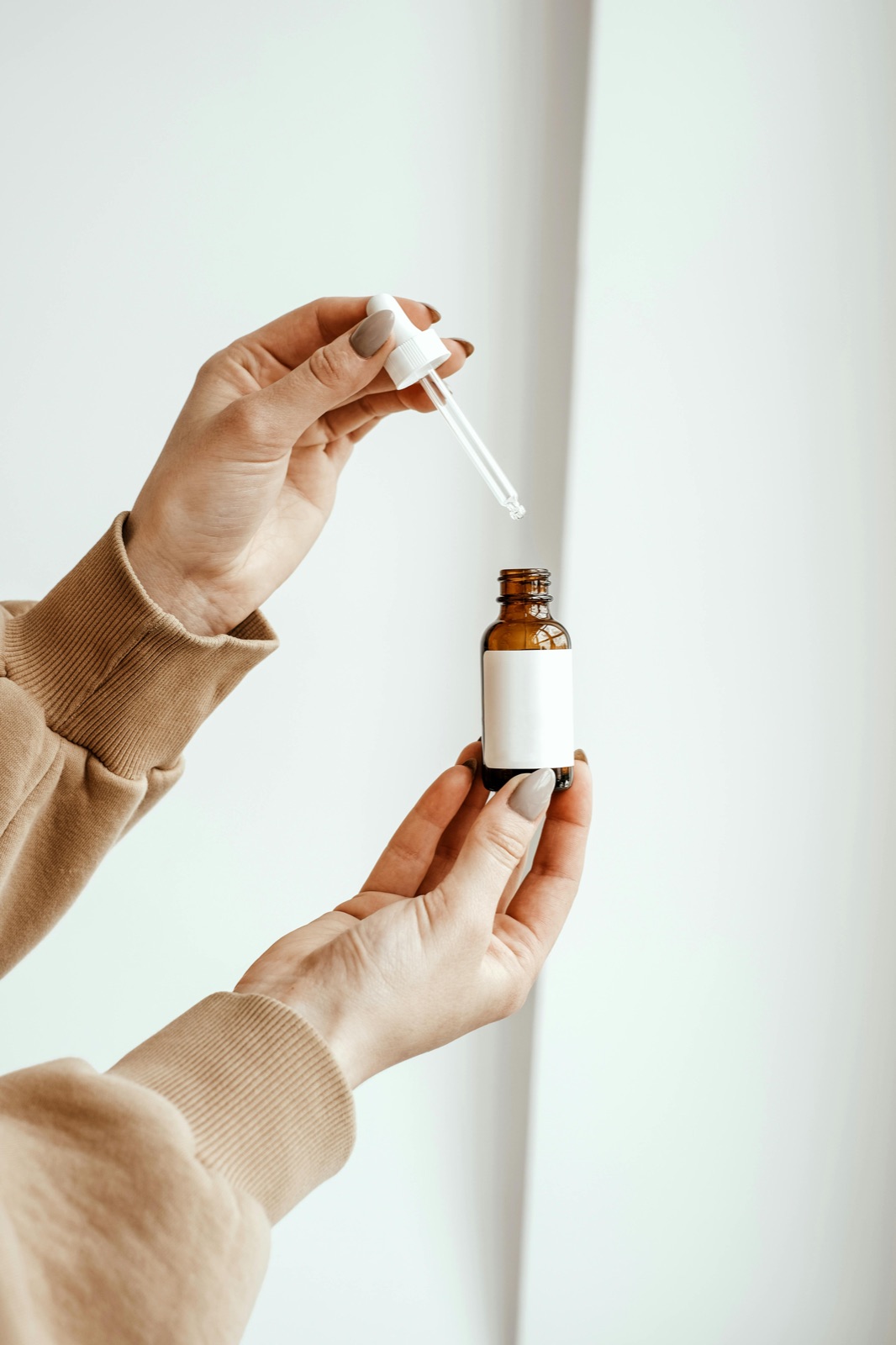 Hand holding a skincare dropper bottle while reading the updated EU INCI ingredient list
