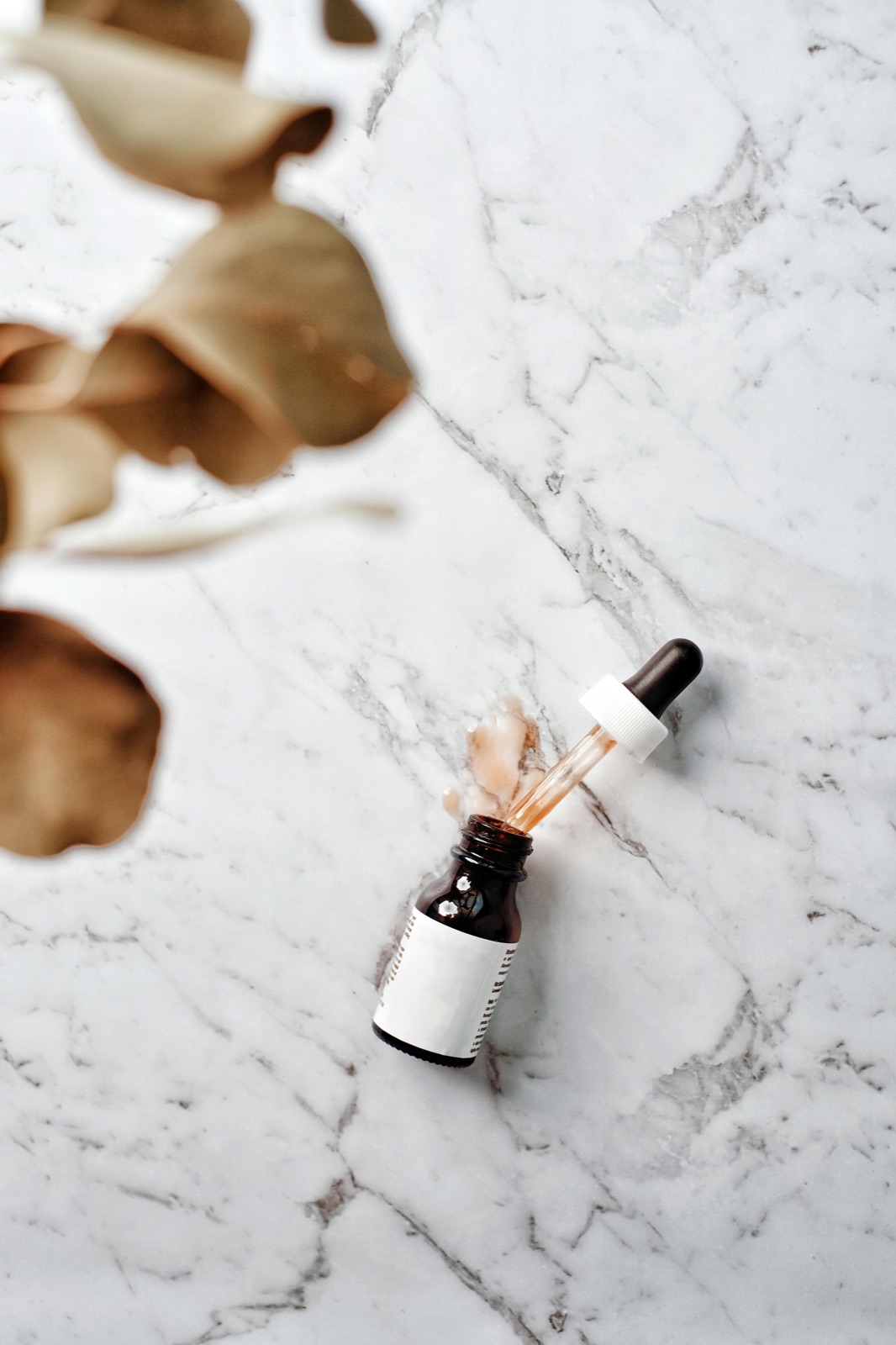 Glass dropper serum bottle on a marble surface representing the act of reading and decoding an INCI ingredient list